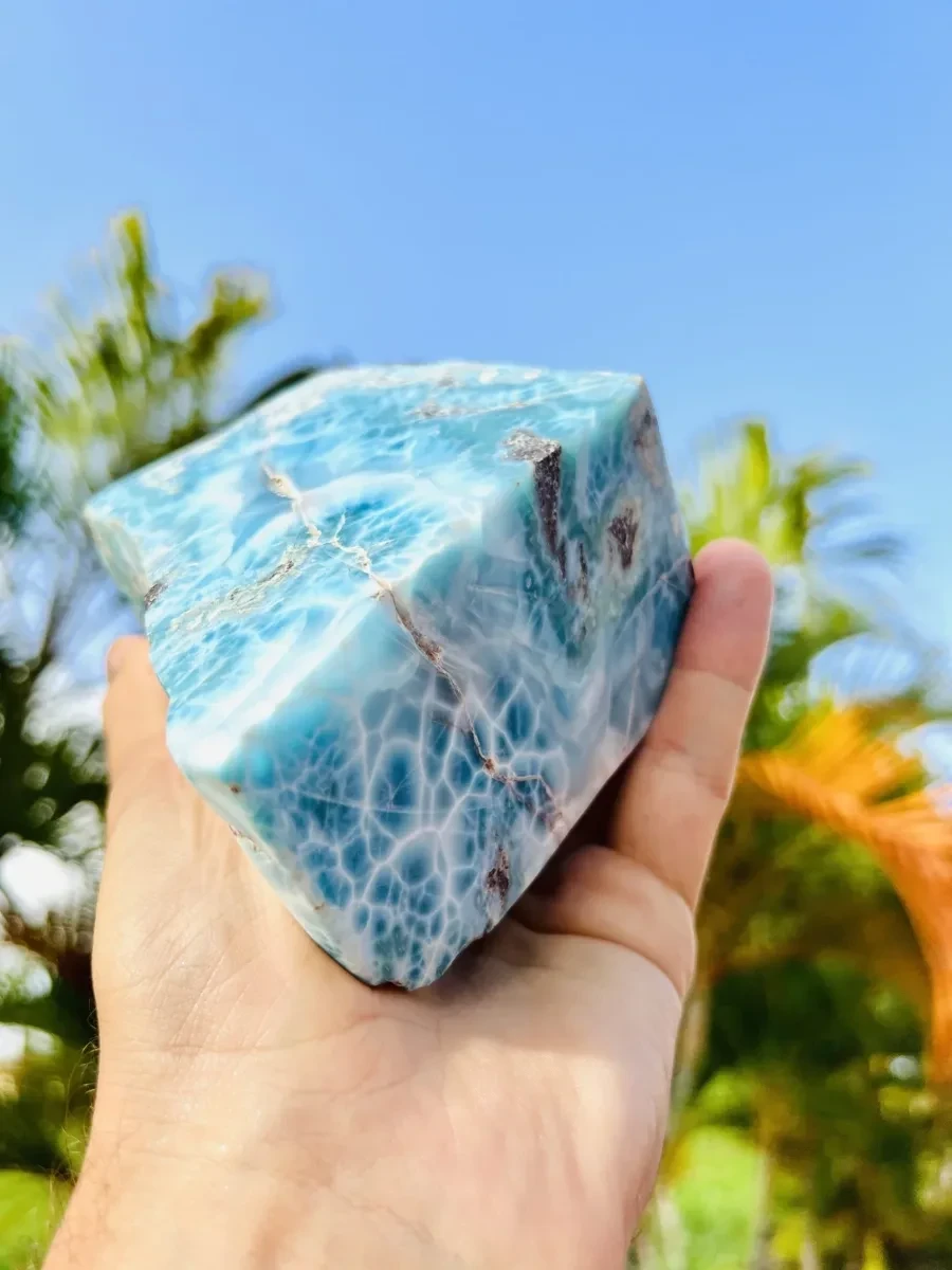 A triangular Larimar rough or slab specimen held outdoors.
