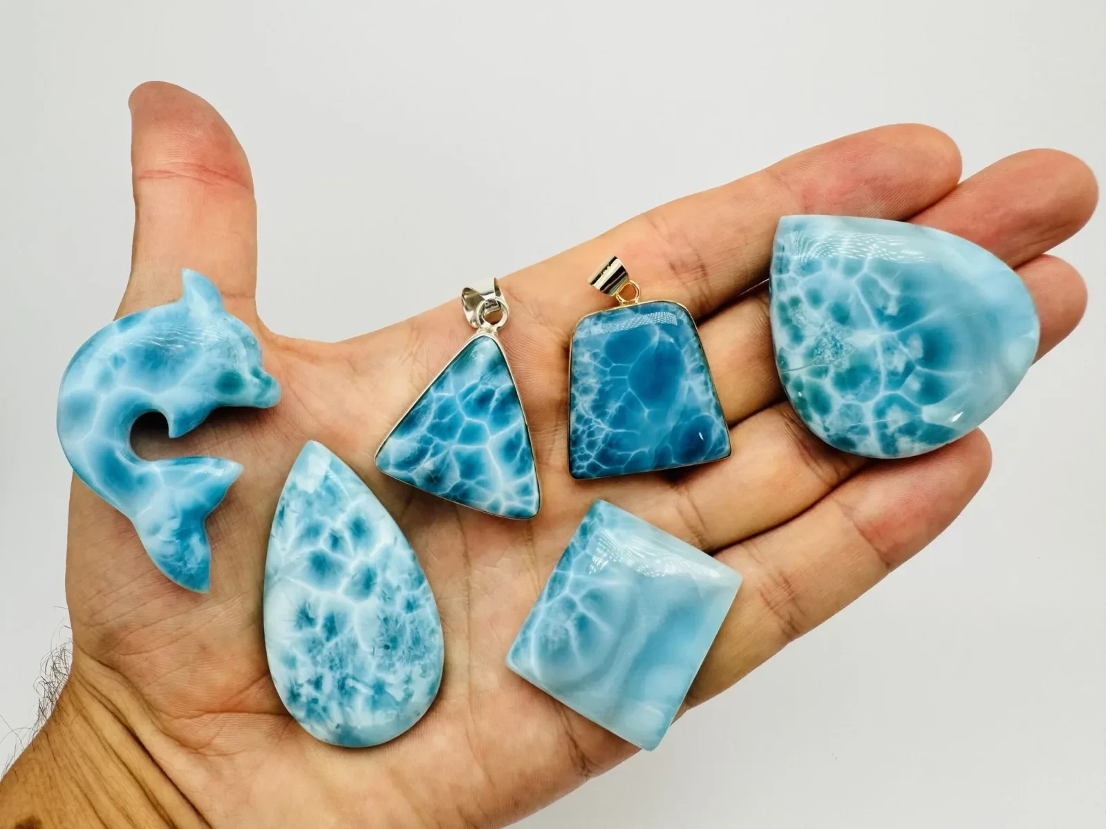 Finished Larimar cabochons, pendants and a carving displayed together.