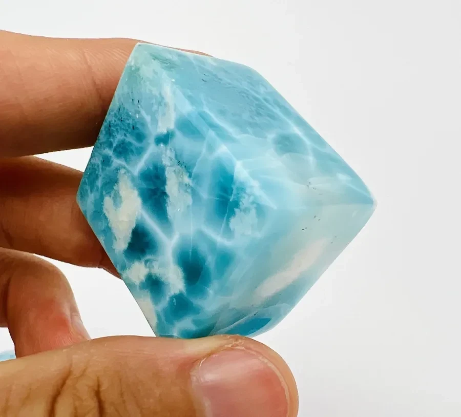 A natural Larimar rough or freeform specimen held for scale.