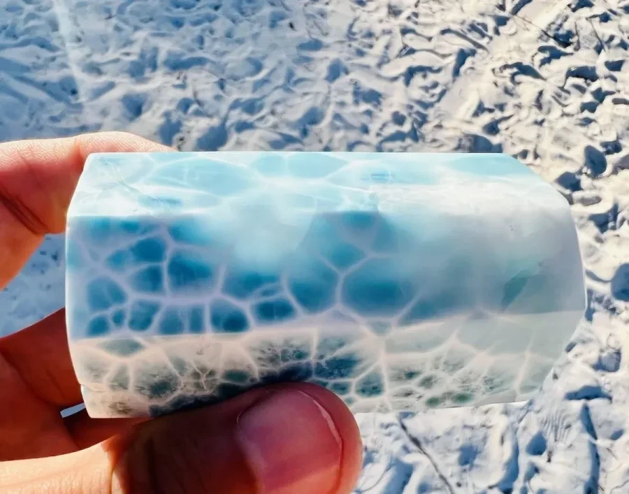 A translucent blue-and-white Larimar tower held beside the sea.