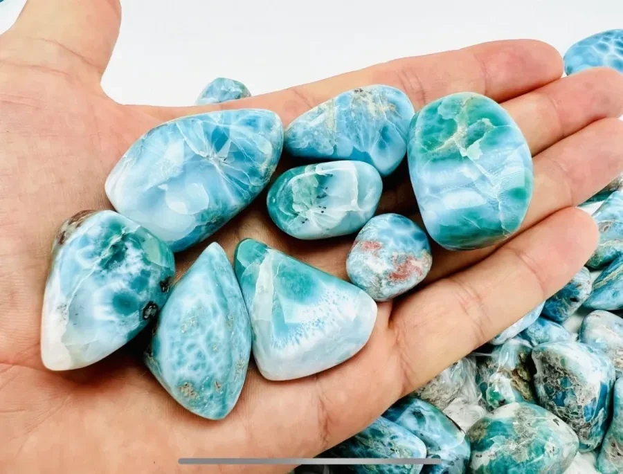 A hand holding several polished Larimar stones.