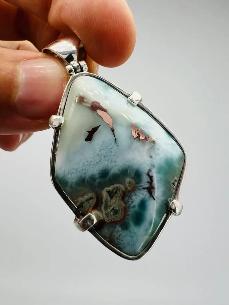 A polished Copper Larimar pendant with visible dark inclusions.